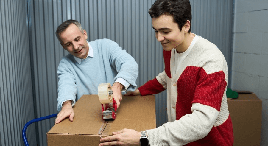 Parent and adult child packing a moving box together